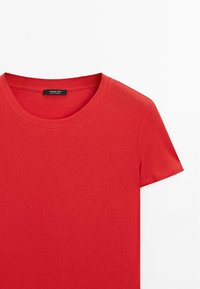 Rød bomulds T-shirt med rund halsudskæring og korte ærmer. Glat tekstur med et mærke, der har "Massimo Dutti" på ryggen.