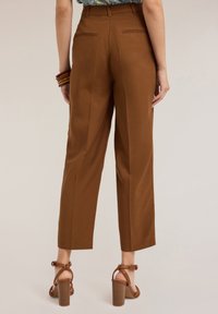 Pantalons marron taille haute avec une jambe droite, dotés de poches arrière, associés à des sandales à talons blocs marron strappées.