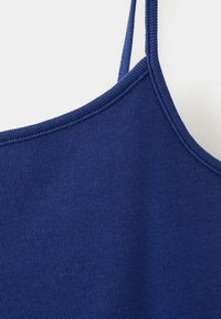 Gros plan sur un débardeur en tissu côtelé bleu marine avec fines bretelles et coutures visibles le long de l'encolure.