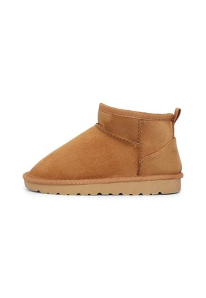 Stivaletto in suede beige con punta rotonda, dettagli cuciti e suola in gomma testurizzata. Presenta un'etichetta sul retro per un facile indossamento.
