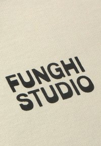 Beige stoffen achtergrond met zwarte tekst "FUNGHISTUDIO" in vetgedrukte, moderne lettertype, met een gestructureerde afwerking.