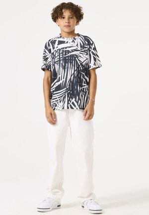 Korte mouwen zwart-wit graphic t-shirt met palmbladeren patroon, gecombineerd met witte broek en witte sneakers. Eenvoudig ontwerp en relaxed fit.