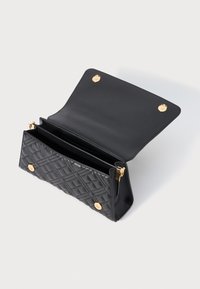 Schwarze, gesteppte Leder-Clutch mit goldenen Druckknöpfen und einem Reißverschlussfach, auf weißem Hintergrund geöffnet gezeigt.