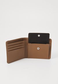 Cartera de cuero marrón con múltiples ranuras para tarjetas y un bolsillo con cierre a presión para monedas. El interior presenta un forro negro contrastante.