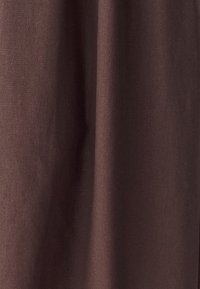 Hnedá bavlnená látka s hladkou štruktúrou, ktorá má jemné odchýlky v odtieni a jednoduchý, bez vzoru dizajn.