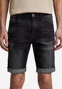 Black denim shorts with a faded finish, rolled hems, front pockets, and a metal button closure, featuring a smooth texture.