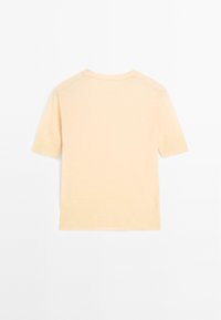 Kurzärmliges, Rundhalsoberteil in hellem Pfirsich, aus weichem Strickstoff gefertigt. Einfaches Design mit einem leicht lockeren Schnitt und gerippten Abschlüssen.