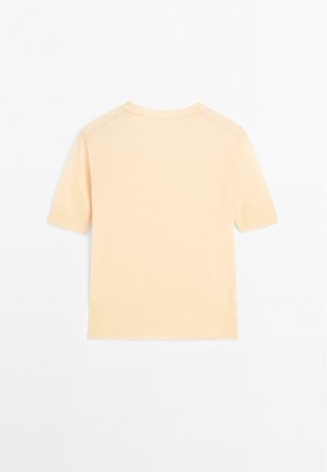 Koszulka z krótkim rękawem, z okrągłym dekoltem w jasnym brzoskwiniowym kolorze, wykonana z miękkiego dzianiny. Prosty fason z lekko luźnym krojem i prążkowanymi krawędziami.