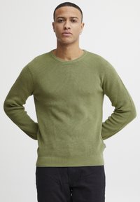 Strickpullover in Olivgrün mit gerippter Textur, rundem Halsausschnitt und langen Ärmeln. Einfarbig ohne sichtbare Muster oder Akzente.