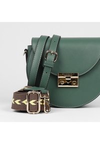 Borsa a tracolla in pelle verde con patta curva, ferrature color oro e tracolla marrone con motivo e accenti gialli.