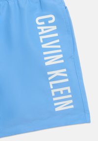 Ανοιχτό μπλε ύφασμα με λευκό κείμενο "CALVIN KLEIN" εκτυπωμένο κάθετα κατά μήκος της πλευράς.