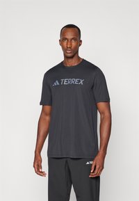 Sorte kortærmet t-shirt lavet af letvægtigt stof, med et fremtrædende blåt "TERREX" logo på tværs af brystet. Simpelt design, rund hals.