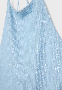 Tissu bleu clair avec des paillettes densément cousues et de fines bretelles, montrant un gros plan d’un vêtement sans manches scintillant.