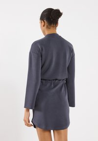 Tumehall sweatshirt-kleit pikkade varrukatega, pitsitatud taljega ja ümarate servadega. Pehme tekstuur väheste disainielementidega.