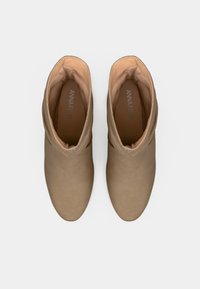 Béžové členkové čižmy s hladkým semišovým povrchom, zaoblenou špičkou a mäkkou podšívkou. Vložky majú označenie „ANNA FIELD“.