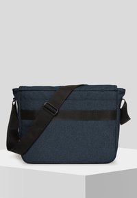Borsa a tracolla blu navy con un tessuto testurizzato, cinturino nero regolabile e una striscia orizzontale decorativa sul davanti. Forma rettangolare.