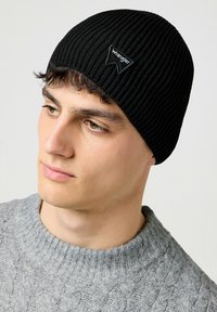 Gorro de punto acanalado negro con un parche del logo triangular de Wrangler. Tejido texturizado, ajuste ceñido y diseño minimalista.