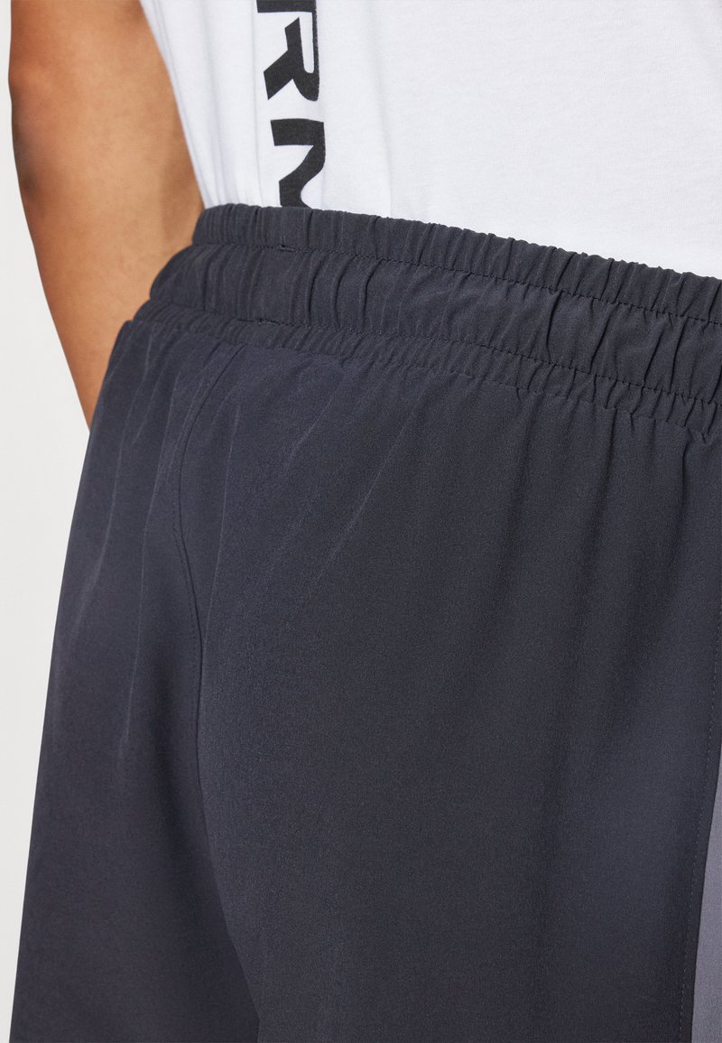 Shorts sportivi blu navy con vita elasticizzata e tasche laterali. Tessuto leggero e liscio con un leggero brillantezza e caduta.