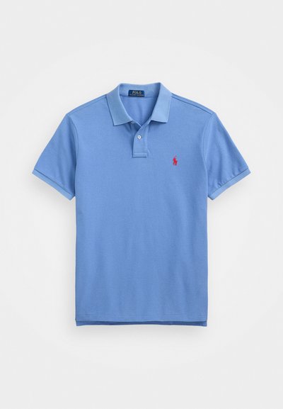 Gaiši zils polo krekls, kas izgatavots no mīksta kokvilnas auduma. Tam ir apkakles neck, īsās piedurknes un neliels sarkans logotips kreisajā krūtī.