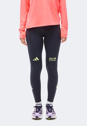 Rajstopy z logo BMW Berlin Marathon i Adidas noszone z różowym topem z długim rękawem oraz fioletowymi butami do biegania, pokazane od talii do stóp.