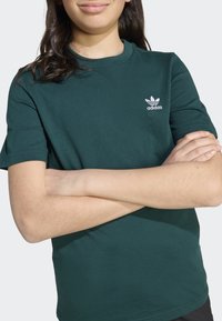 Zöld pamut póló bordázott kerek nyakkal és rövid ujjakkal. Bal mellkasán fehér Adidas logó található. Puha tapintású.