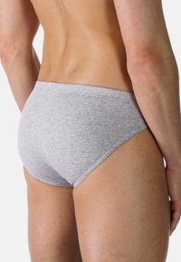 Grå bomullsboxerkalsonger med en mjuk textur, låg midja och elastisk midjeband synlig på baksidan. Enkelt, odekorerat stil.