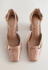 Nude patent leather korkokengät, joissa on neliömäinen kärki, solkiyksityiskohta ja nilkkahihna. Sujuva pinta ja kiillotettu viimeistely.