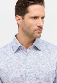 Camicia azzurro chiaro con motivo paisley, colletto classico e bottoni blu. Tessuto morbido con una vestibilità moderna.