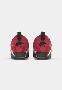 Un par de zapatillas Nike Air rojas vistas desde la parte trasera, con detalles en negro y blanco y tiradores negros.