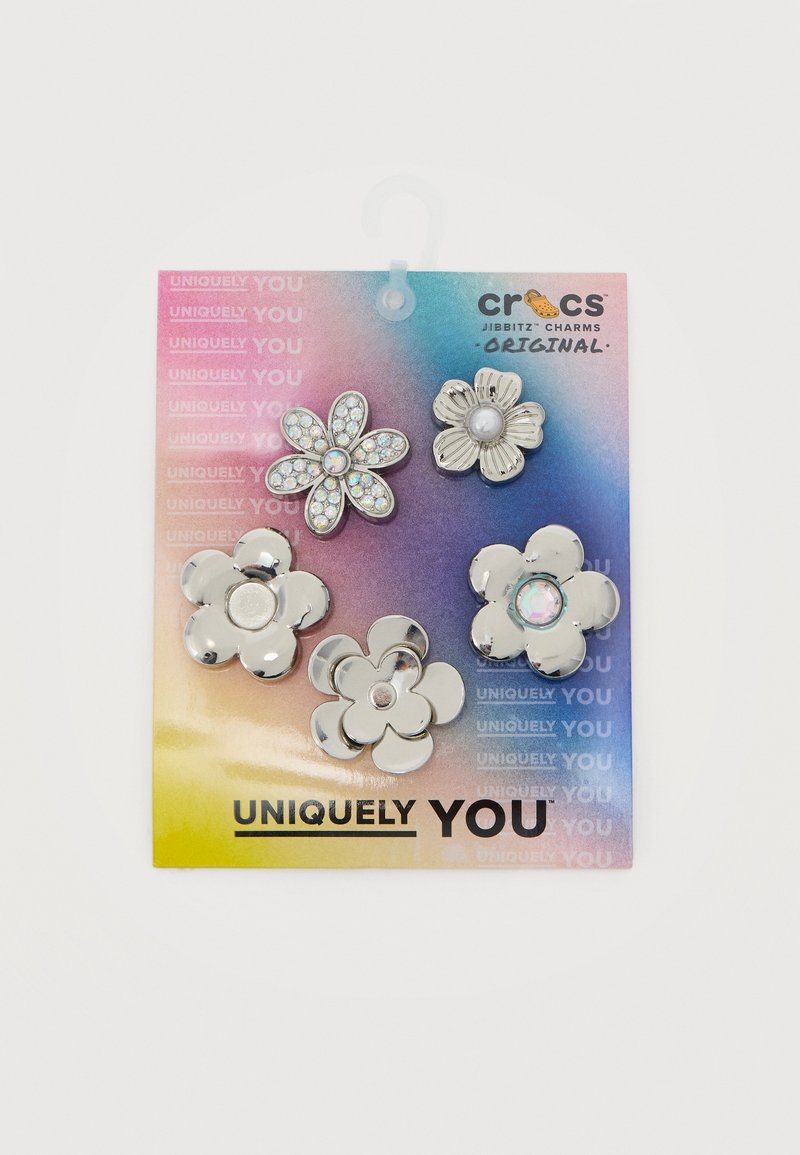 Cinq breloques Crocs Jibbitz argentées en forme de fleur sur une carte arc-en-ciel dégradée avec le texte « Uniquement Vous ».