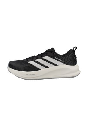 Zapatilla de running Adidas Supernova en blanco y negro con parte superior de malla, tres franjas, suela acolchada etiquetada como Dreamstrike y lengüeta para tirar en el talón.