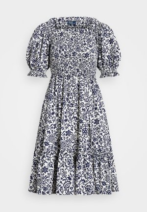Robe blanche avec motif floral bleu marine, manches bouffantes, corsage froncé et jupe à volants. Fabriquée en tissu léger avec un détail froncé.