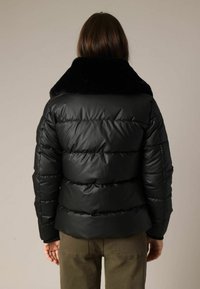 Zwarte donsjas met een zacht, zwart kraag. Heeft doorgestikte secties en een gladde, glanzende afwerking. Achteraanzicht toont een aansluitend ontwerp en naaddetails.