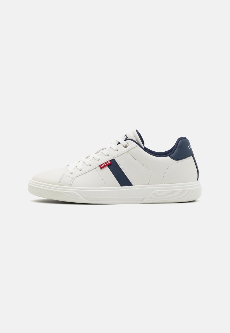 Baskets basses blanches avec des accents bleu marine, des lacets blancs et une étiquette rouge avec le logo Levi's sur le côté, présentées sur un fond blanc uni.