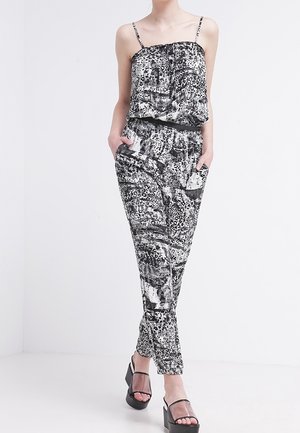 Mustavalkoinen kuvitettu haalari, jossa on löysä yläosa, säädettävät spagettihihnat ja kapeat lahkeet. Sisältää erilaisia abstrakteja kuvioita.