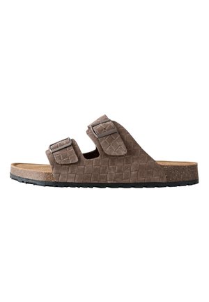Braune Wildleder-Slidesandale mit zwei verstellbaren Schnallenriemen und einer strukturierten Korksohle mit schwarzer Gummiaußensohle.