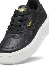 Mustat nahkakengät mustilla nauhoilla, rei'itetty kärki, valkoinen teksturoitu pohja ja kultaiset detaljit. PUMA-logo kielekkeellä ja sivussa.