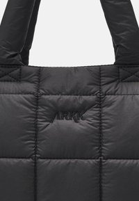 Czarna pikowana torba z materiału z wyściełanymi uchwytami i haftem "ARKK" w czarnym kolorze na przednim centralnym panelu.