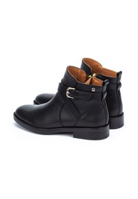 Bottines noires en cuir avec un faible talon, dotées d'un accent en boucle dorée, texture lisse et intérieur beige. Couture détaillée sur les côtés.