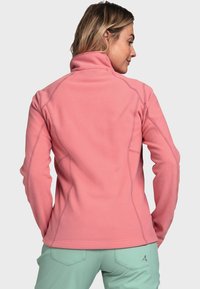 Fleece-Jacke in Hellpink, mit hohem Kragen und langen Ärmeln, sichtbaren Nähten und einer glatten Textur.