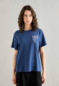 Navy blue cotton t-shirt with short sleeves, featuring "island girl" embroidered in pink and white on the left chest. Relaxed fit.