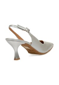 Zapato de tacón alto plateado tipo slingback con punta afilada, parte superior metálica lisa, correa ajustable en el tobillo y plantilla texturizada marrón.