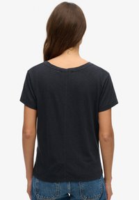 Camiseta gris oscuro con un corte holgado y mangas cortas. Presenta un cuello redondeado y costuras visibles en la parte posterior. Textura suave.