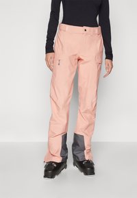 Light pink snow pants with gray accents, made of waterproof material. Features include pockets and a secure waistband. Suitable for winter sports.