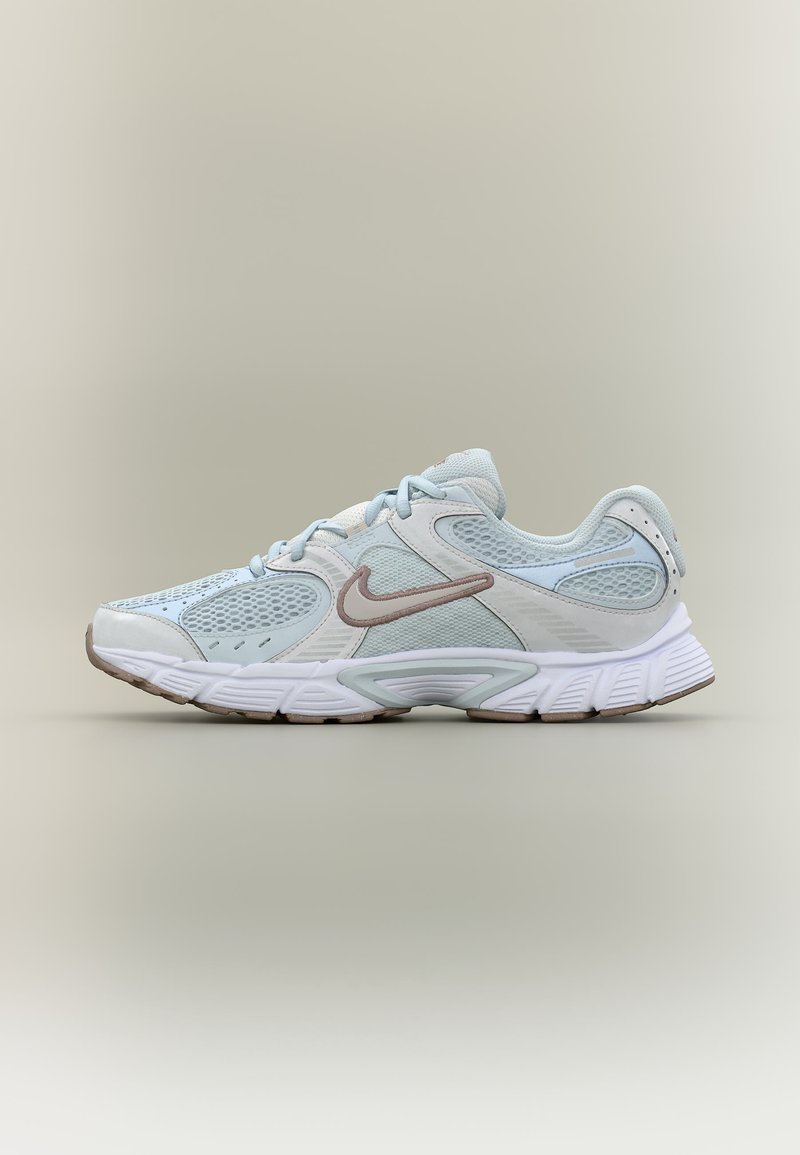 Hellblauer und weißer Nike-Laufschuh mit Mesh-Einsätzen, beigem Swoosh-Logo und dicker gepolsterter Sohle vor neutralem Hintergrund.