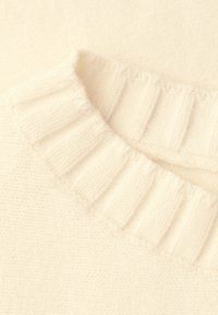 Suéter crema con cuello acanalado, textura suave y un tejido de punto liso con un color uniforme en toda su superficie.