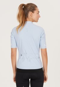 Lichtblauw fietsjersey met korte mouwen, gestroomlijnd ontwerp, contrasterende zwarte tailleband en achterzakken met reflecterende details.