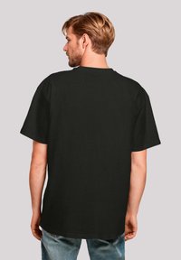 Schwarzes T-Shirt mit kurzen Ärmeln, lässiger Passform und Rundhalsausschnitt, glatte Textur und ohne sichtbare Muster oder Logos, von hinten betrachtet.