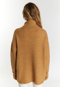 Rdzawoczerwony, oversize'owy sweter z dzianiny z wysokim kołnierzem i opuszczonymi ramionami. Miękka faktura i żebrowane akcenty przy mankietach oraz u dołu.