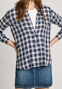 Mörkblå och vit rutigt skjorta med knappar och lång ärm, två bröstfickor och lätt tyg, kombinerad med en denimkjol.